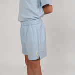 Glacial blue sports shorts, side on with yellow Svante logo detail on left leg on a plain studio background.
