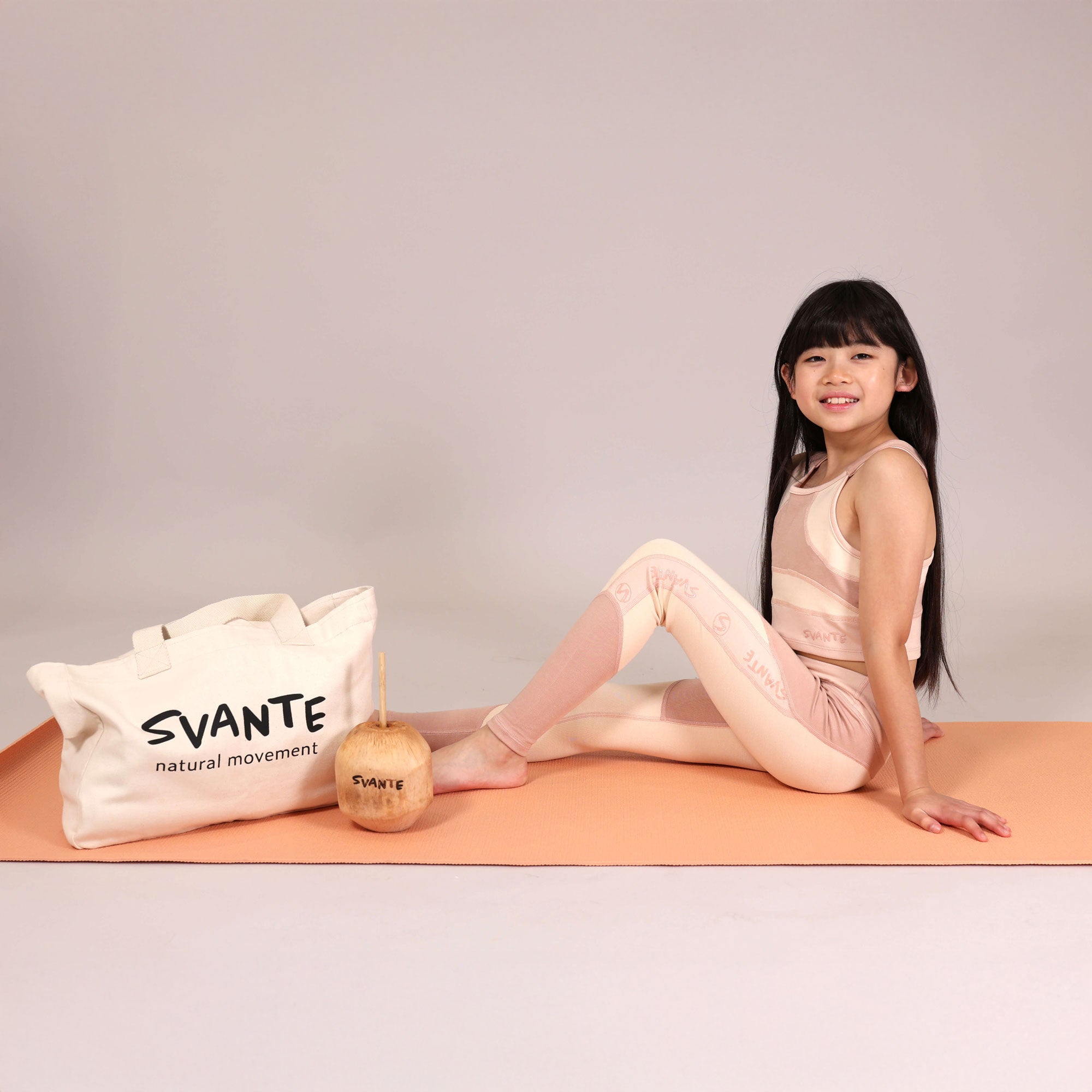 Chinese girl sitting on orange yoga matt with organic cotton Svante Tote bag and wearing natural material sports leggings and sports crop top