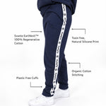 A girl wearing Svante regenerative cotton navy sweatpants with a white side stripe printed with the brand name Svante, shown from the waist down on a white background with feature callout text overlays. 