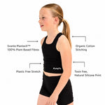 A young girl wearing a Svante plant plant based black sports crop top and matching black sports shorts stands in profile against a white background, with callout text highlighting product features such as Svante Plantech™ 100% plant based fibres, organic cotton stitching, plastic free stretch, and toxin free, natural silicone print.