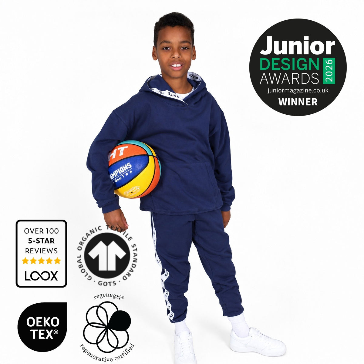A boy model wearing a Svante regenerative cotton navy blue hooded sweatshirt and matching sweatpants with white side stripes, holding a basketball. The image includes award and certification badges on a white background.