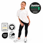 A young girl modelling a Svante polyester free white organic cotton short-sleeve t-shirt and polyester free black sports leggings, standing against a white background with several certification and award badges overlaid on the left and top right.