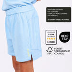 Light blue polyester free boys sports shorts worn by a boy with certification logos on a white background
