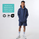 Boy wearing a navy blue organic cotton hoodie and  blue organic cotton jersey shorts with certification logos on a white background. 