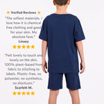 Boy wearing an organic cotton navy blue t-shirt and jersey shorts matching outfit with text on verified reviews. 