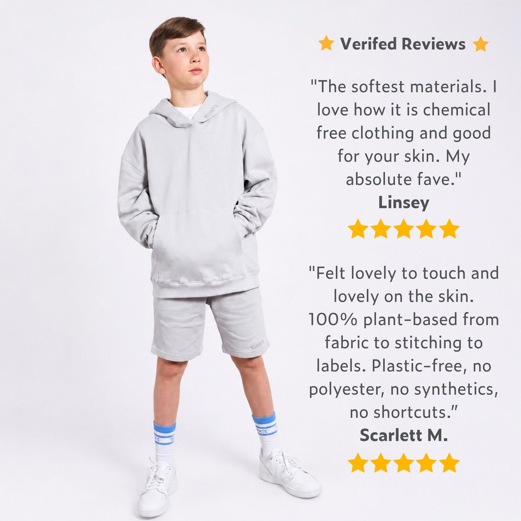Boy wearing a grey organic cotton hoodie and grey organic cotton jersey shorts with positive reviews displayed on a white background. 