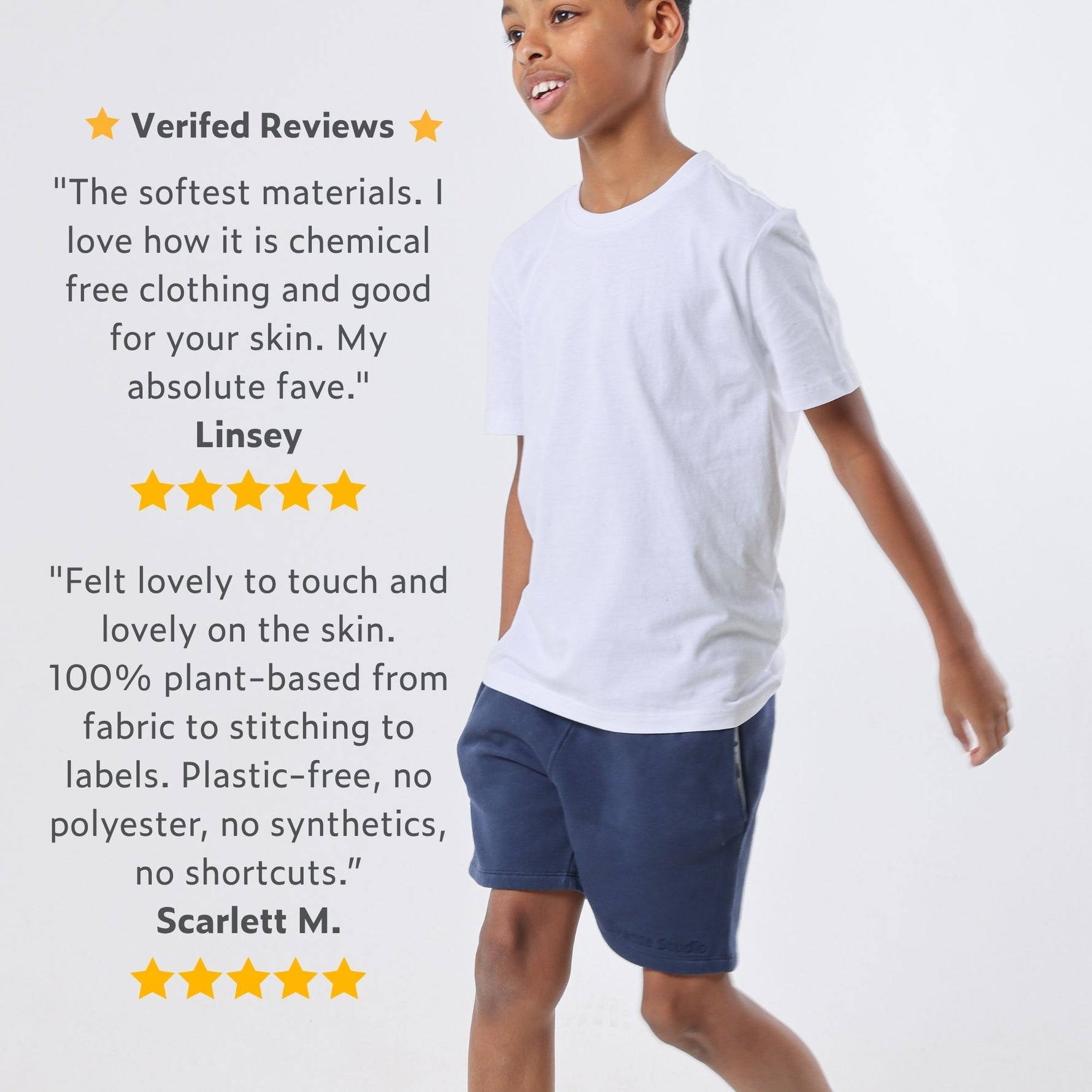 Boy wearing an organic cotton white t-shirt and blue organic cotton jersey shorts with positive reviews on a light gray background. 