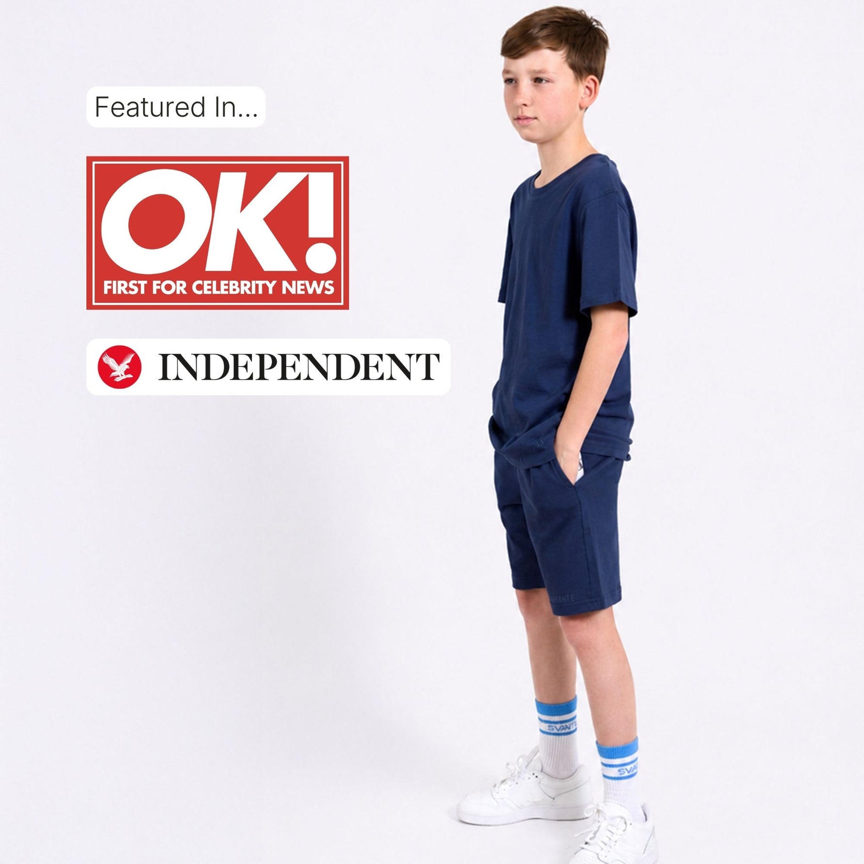 Young boy in navy organic cotton t-shirt and jersey shorts with OK! and Independent logos on a white background. 