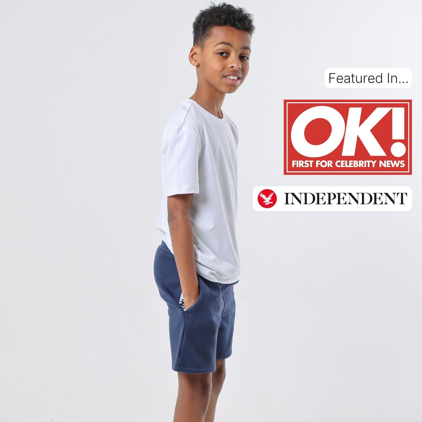 Boy wearing a regenerative cotton white t-shirt and blue organic jersey shorts on a white background with OK! and Independent logos. 