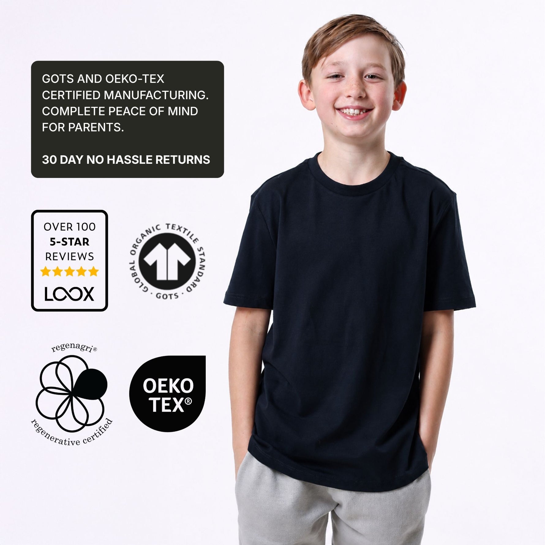 Boy wearing an organic cotton navy blue T-shirt with certification logos on a white background. 