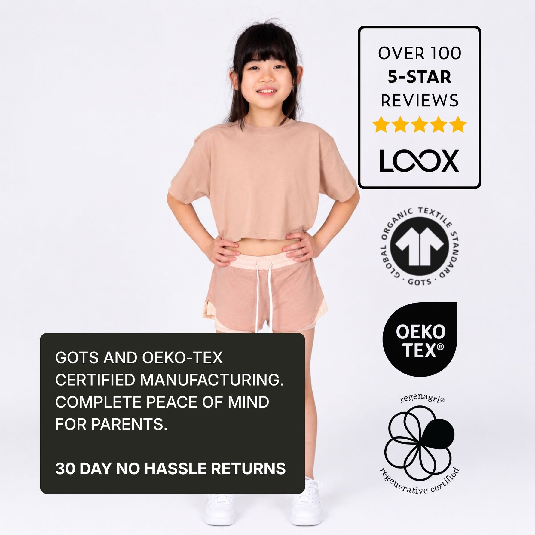 Girl wearing a pink organic cotton crop t-shirt and polyester free pink sports shorts with certification logos and text on a white background. 