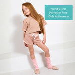 Young girl wearing pink organic cotton crop top and pink sports shorts with text 'World's First Polyester Free Girls Activewear' on a white background. 
