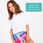Girl wearing white organic cotton crop t-shirt with blue sports shorts with a white background, labeled 'World's First Polyester Free Girls Activewear'. 
