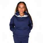 Girl with long braided hair wearing a Svante regenerative cotton navy blue sweatshirt and matching sweatpants, featuring a white inner hood lining with black text. 