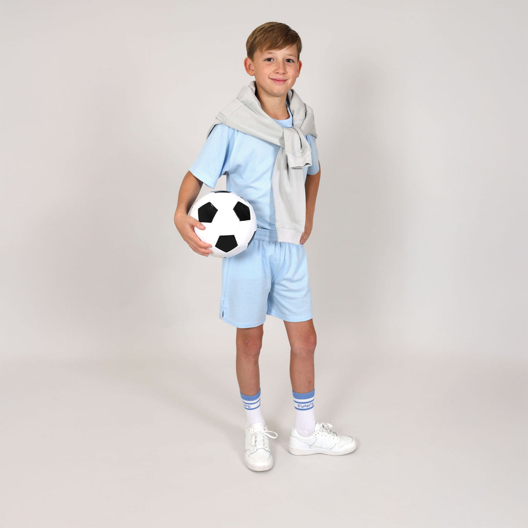 Boy wearing Svante Glacial Blue sports shorts and sports t-shirt set made from 100% natural, plastic-free and toxin-free materials.